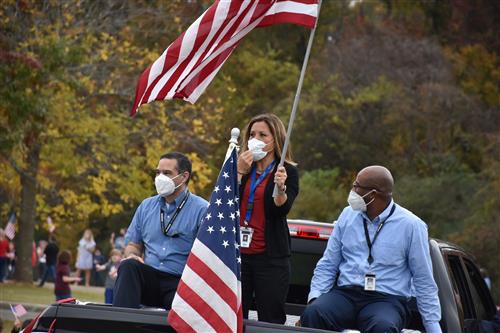 Board members in back of pickup waving flag 